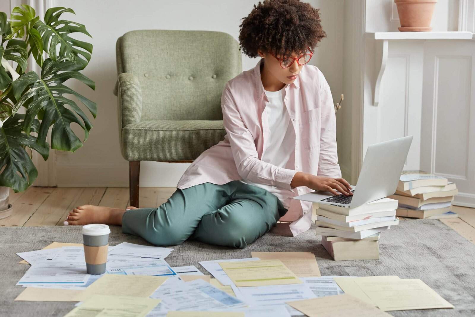 Empreendedorismo: tudo que você precisa para dominar seu fluxo de caixa - Mulher sentada no chão do apartamento organizando as contas