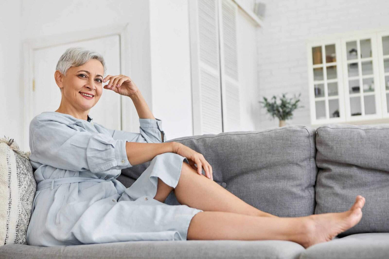 Renovando as energias de casa: dicas de decoração e acessórios para ambiente de calmaria - Mulher sentada no sofá