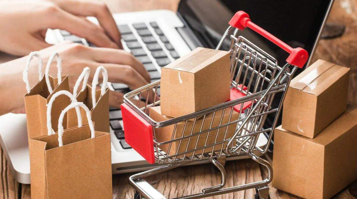 Pessoa fazendo compras pelo notebook e carrinho de compras sobre a mesa com caixas fechadas ilustrando os diferentes tipos de produtos que vendem fácil.