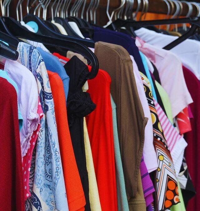 Roupas coloridas e variadas expostas em cabides, representando o estoque de moda disponível para revenda em um modelo de negócio de varejo
