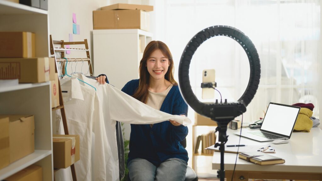 Mulher com cabelos longos e escuro, representando uma criadora de conteúdo, apresentando roupas em vídeo com ring light.